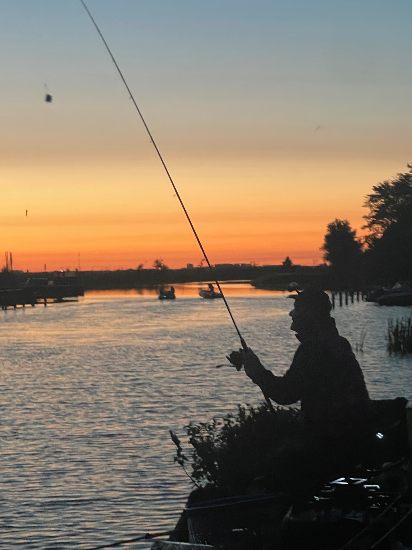 Visser aan het Drentsche Diep bij een oranje zonsopkomst